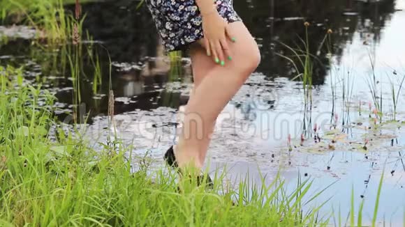 女孩站在水库附近用双手驱赶蚊子双手坐在她的脚上视频的预览图