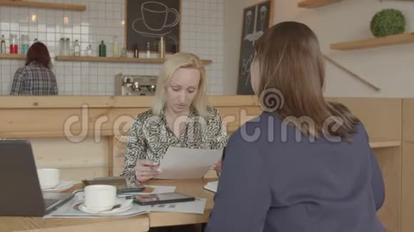 女商人在咖啡馆里读保险单视频的预览图