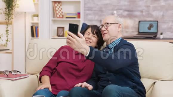快乐的老夫妇坐在沙发上自拍视频的预览图
