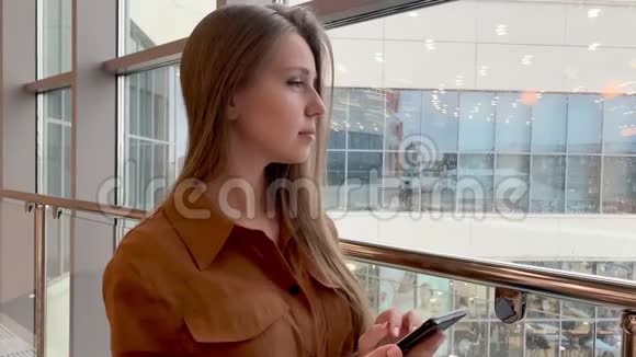 在办公室内用手机浏览微笑的年轻商务女性特写视频的预览图