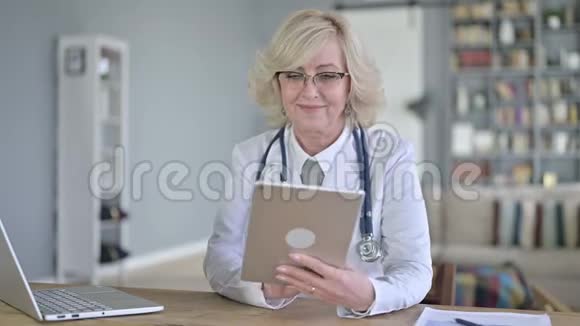 老年女医生在桌上做视频聊天视频的预览图