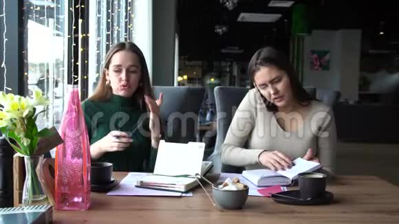 两个迷人的微笑的女商人一起工作坐在室内咖啡馆里视频的预览图
