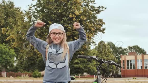 一个11岁的女孩在夏天的时候在她的自行车旁边心情很好地竖起大拇指视频的预览图