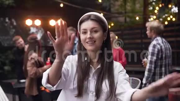 漂亮的微笑着的年轻女士长发在花园里的同伴身边用手举起相机跳舞视频的预览图