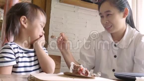 亚洲母亲在咖啡馆吃蛋糕时擦了擦女儿的嘴视频的预览图
