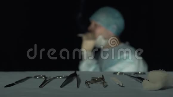 劳累的外科医生在医院做手术或做手术后抽烟专注于手术器械如手术刀视频的预览图