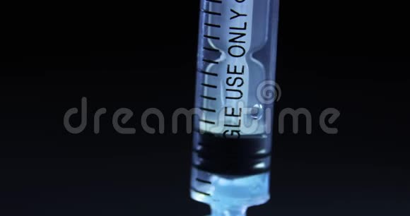 在黑色背景下将蓝色冠状病毒疫苗拨入注射器特写视图视频的预览图
