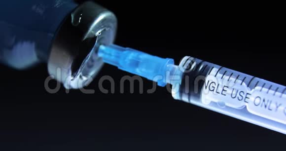 在黑色背景下将蓝色冠状病毒疫苗注射到注射器中COVID19视频的预览图