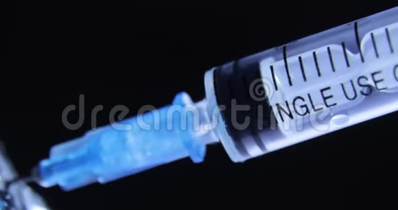 将蓝色冠状病毒疫苗接种到黑色背景下的注射器中视频的预览图