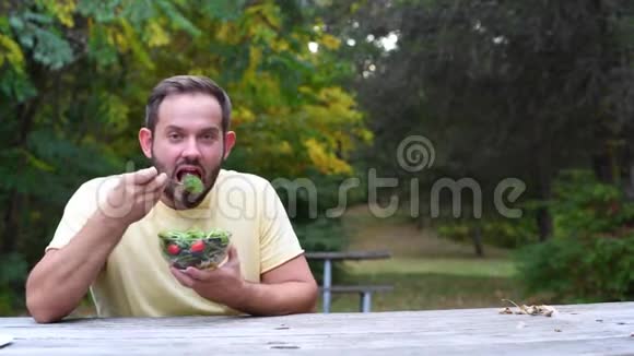 坐在公园里吃新鲜沙拉的人健康素食食品视频的预览图