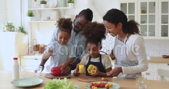 快乐的非洲父母教孩子们切沙拉烹饪厨房视频的预览图