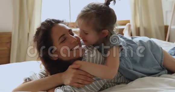 可爱的小女儿拥抱亲吻妈妈躺在床上视频的预览图
