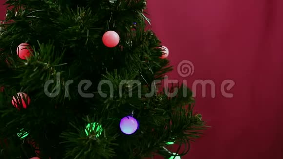 小女孩的手在圣诞树上挂一个绿球女孩装饰圣诞树视频的预览图