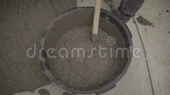 建筑工人正在使用干灰泥和水用电动搅拌机将其混合在桶中特写镜头建设概念视频的预览图