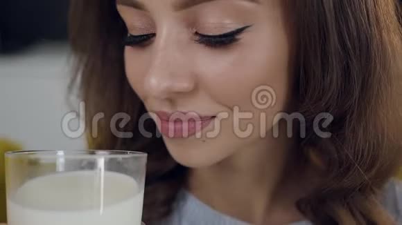 可爱的快乐满足的女人喝着一杯牛奶真诚地微笑着在镜头上摆姿势视频的预览图