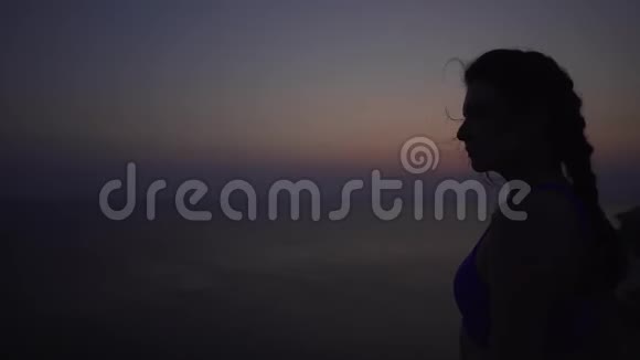 一个年轻美丽的白种人女孩的剪影日出前的海洋背景大风最后报告视频的预览图
