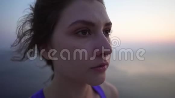 一个年轻女孩的特写肖像一个穿紫色上衣的运动员在冥想前呼吸折叠手臂和练习视频的预览图