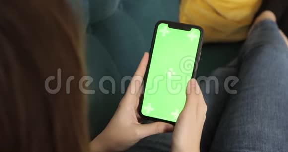 女人正在浏览智能手机绿色屏幕躺在沙发上特写视频的预览图