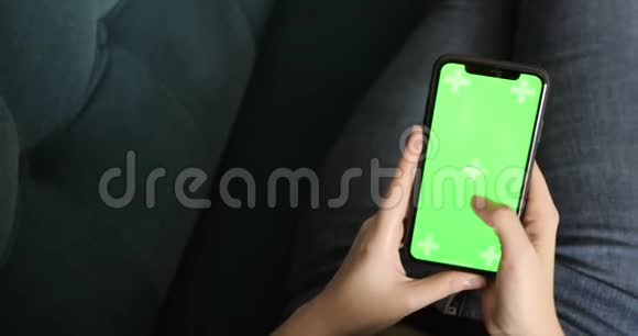 年轻女孩浏览智能手机绿色屏幕躺在沙发上特写视频的预览图