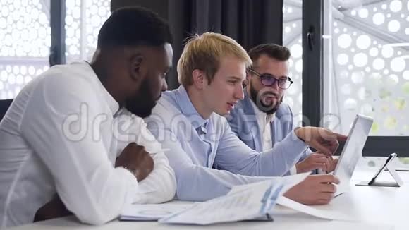 英俊的多种族的30多岁经理在办公室里看电脑屏幕讨论他们的商业计划视频的预览图