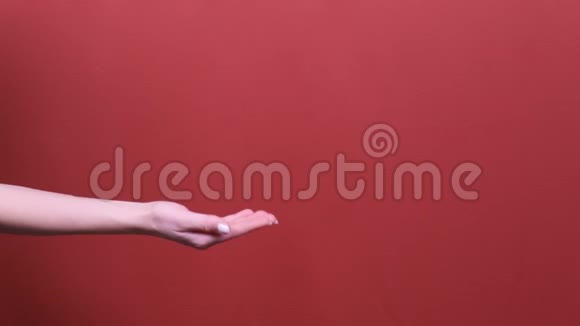 女人的手握着手掌上的铜空间在演播室的红色背景上被隔离视频的预览图
