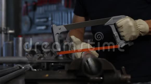 工作人员在车库车间工作台上用钢锯切割金属管夹持在工作台上自己动手构思双手合拢视频的预览图