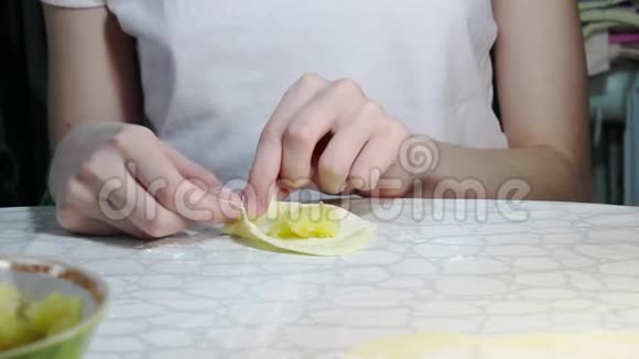 一个十几岁的女孩在餐桌上煮饺子和土豆作为晚餐视频的预览图