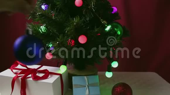 那个年轻女孩手把一个蓝色的球挂在圣诞树上女孩装饰圣诞树视频的预览图