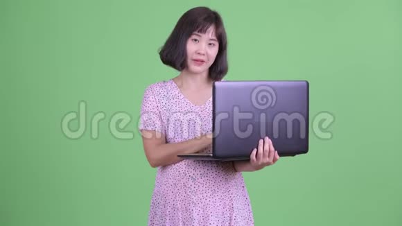 快乐的亚洲孕妇一边说一边用手提电脑视频的预览图
