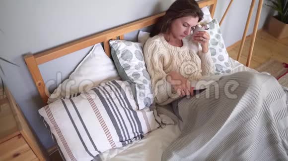 卧室里舒适快乐和舒适床上的女孩读一本书在寒冷的一天辛苦了一天后休息视频的预览图