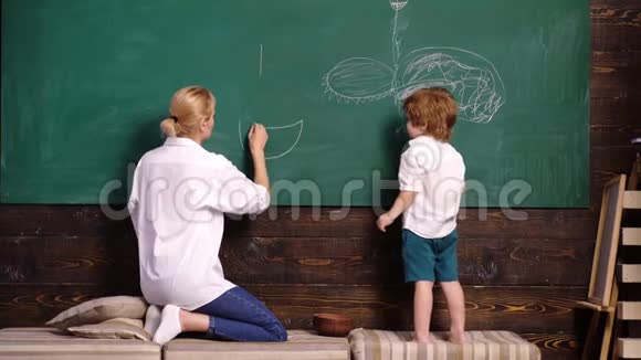 幼儿教师和幼儿男孩在黑板上作画女人和男孩画画母亲和儿子用粉笔在视频的预览图