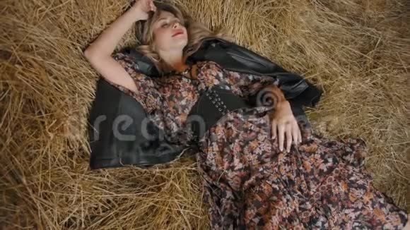 美丽而性感的女孩躺在干草堆上懒洋洋地转过头来视频的预览图