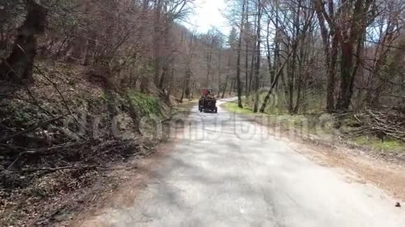 早春在蜿蜒的森林道路上有拖车的小型拖拉机视频的预览图