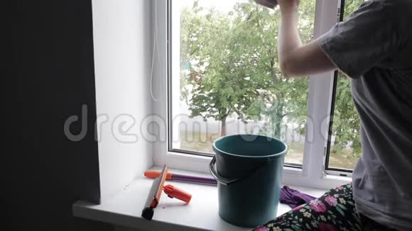 年轻女士正在用清洁剂擦窗户视频的预览图