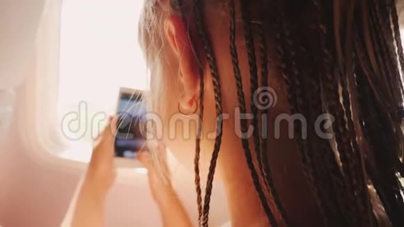 一个女孩从飞机的窗口拍摄风景非洲辫子编织在她的头上带孩子度假视频的预览图