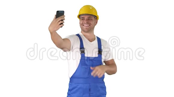 微笑英俊的年轻建筑工人用手机在白色背景上自拍视频的预览图