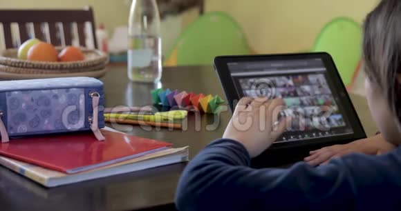 白种人小女孩在隔离期间在家学习使用平板电脑看屏幕在家做学校任务视频的预览图