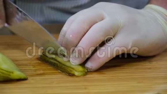 厨师戴橡胶手套用刀在木竹砧板上切腌黄瓜视频的预览图