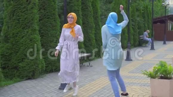 两个笑容满面的穆斯林女孩在街上跳舞视频的预览图