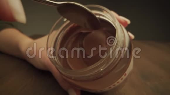 玻璃罐与美味的巧克力奶油和勺子隔离在白色顶部视图巧克力酱用勺子从视频的预览图
