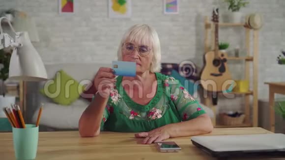 一位头发灰白体贴的老妇人拿着银行卡视频的预览图