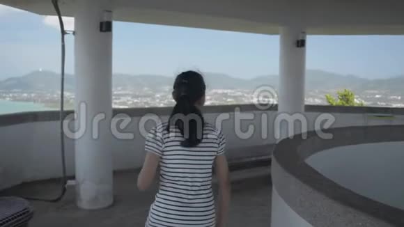 亚洲可爱的女孩穿着休闲装冲进观景塔欣赏海岸上的美丽景色视频的预览图