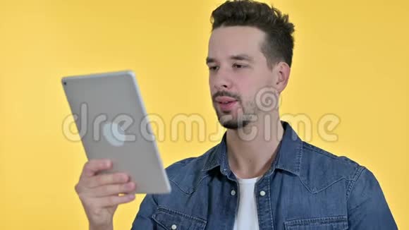 年轻人在平板电脑上视频聊天的肖像黄色背景视频的预览图