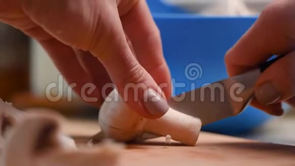手指上有漂亮指甲的女性用菜刀在蓝色塑料切割板上切割蘑菇视频的预览图