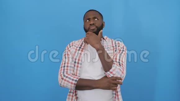 年轻的非裔美国男子穿着t恤站在蓝色背景上手指着成功的手指视频的预览图