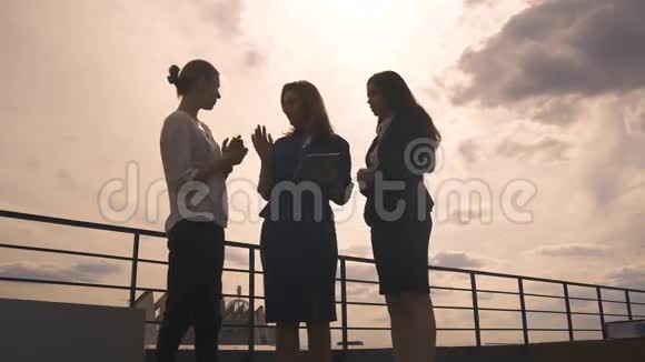 一群商人的剪影妇女对抗天空和云彩在会议上穿商务服的女孩视频的预览图