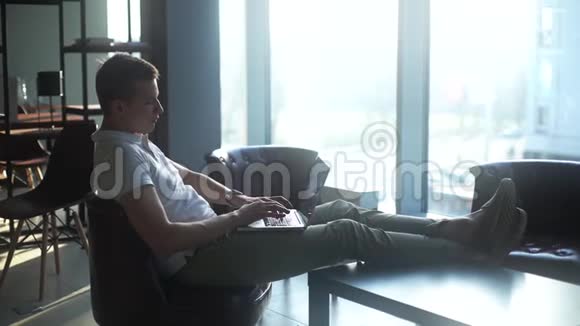 自信的年轻商人在笔记本电脑上打字把脚放在咖啡桌上视频的预览图