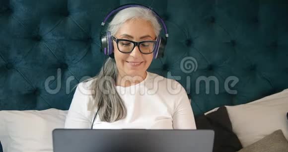 有手提电脑唱歌的老年妇女视频的预览图