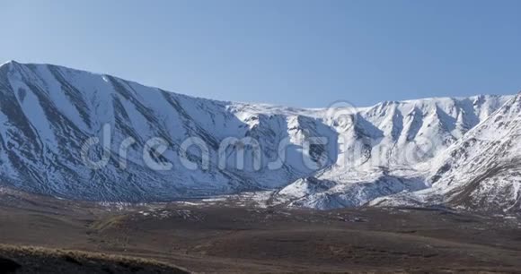 雪山顶上晶莹剔透的天空上太阳运动的时间推移秋天草地上的黄草无边无际视频的预览图