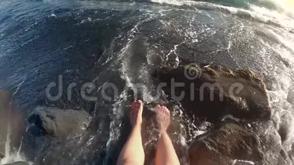 坐在沙滩上的男性脚上海浪翻滚和断裂的慢动作视频视频的预览图